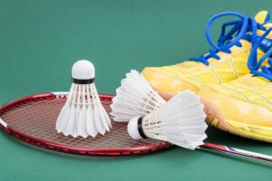 Three badminton shuttlecock with racket and shoes on green court